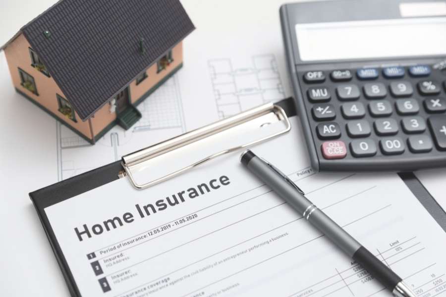Un contrat d'assurance habitation avec une maquette de maison et une calculatrice.
