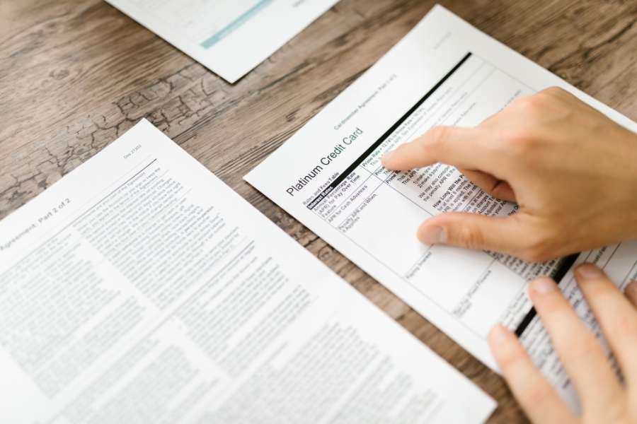 Une personne analyse attentivement un contrat pour réduire ses frais bancaires sur des documents financiers.
